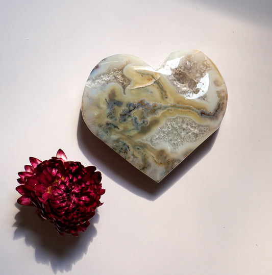 Close-up of a grey moss agate heart with warm amber veining, alternate angle