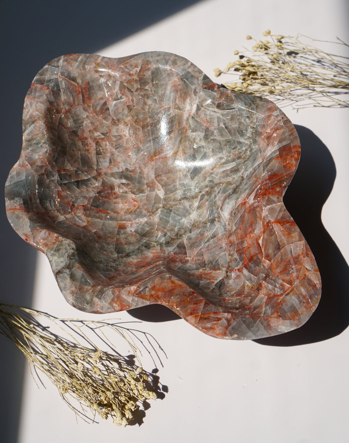 Empty Blue Calcite hematite bowl styled with dried florals on a sunlit white background