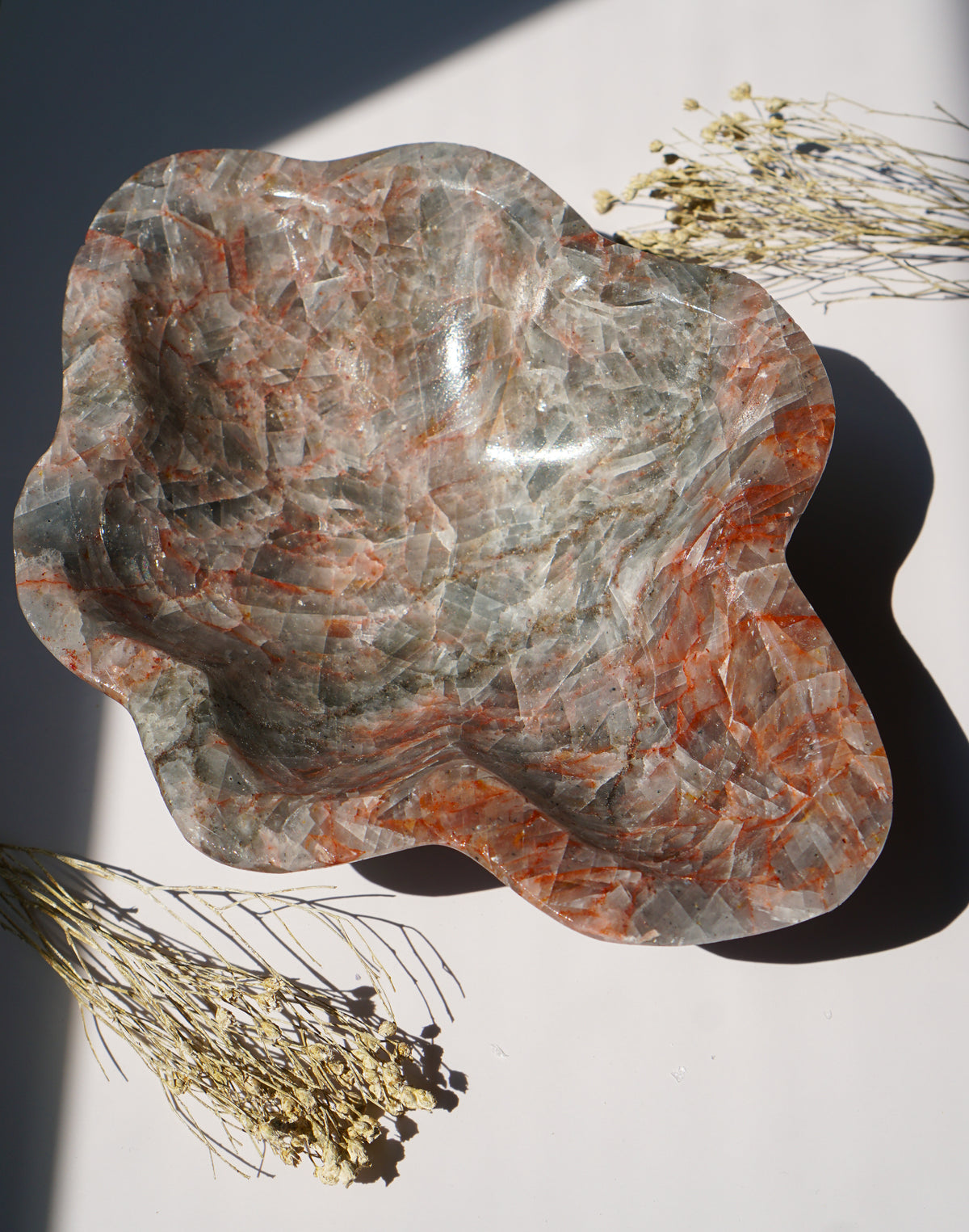 Empty Blue Calcite hematite bowl styled with dried florals on a sunlit white background