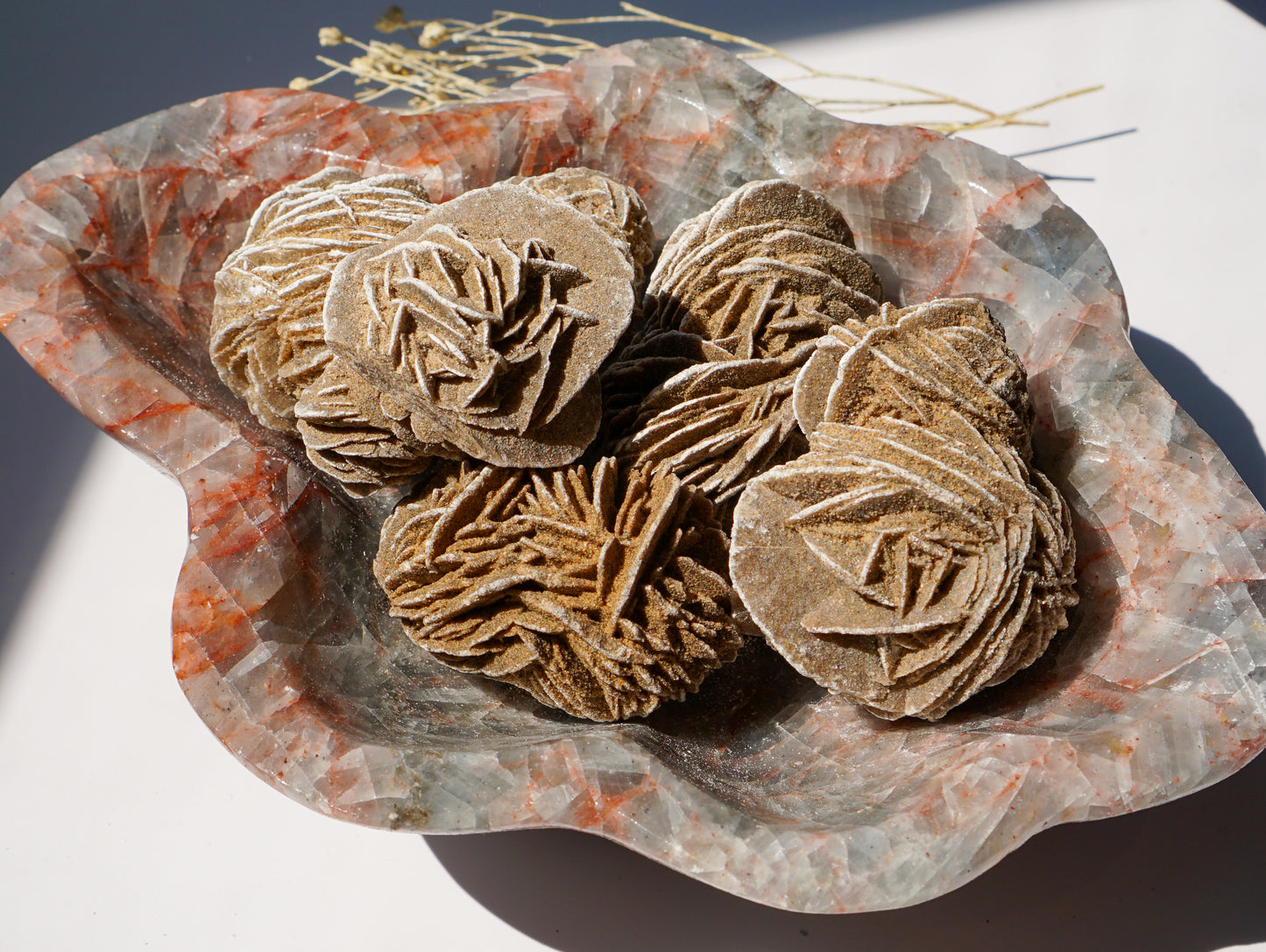 Blue Calcite hematite bowl filled with desert rose selenite clusters, close-up angle