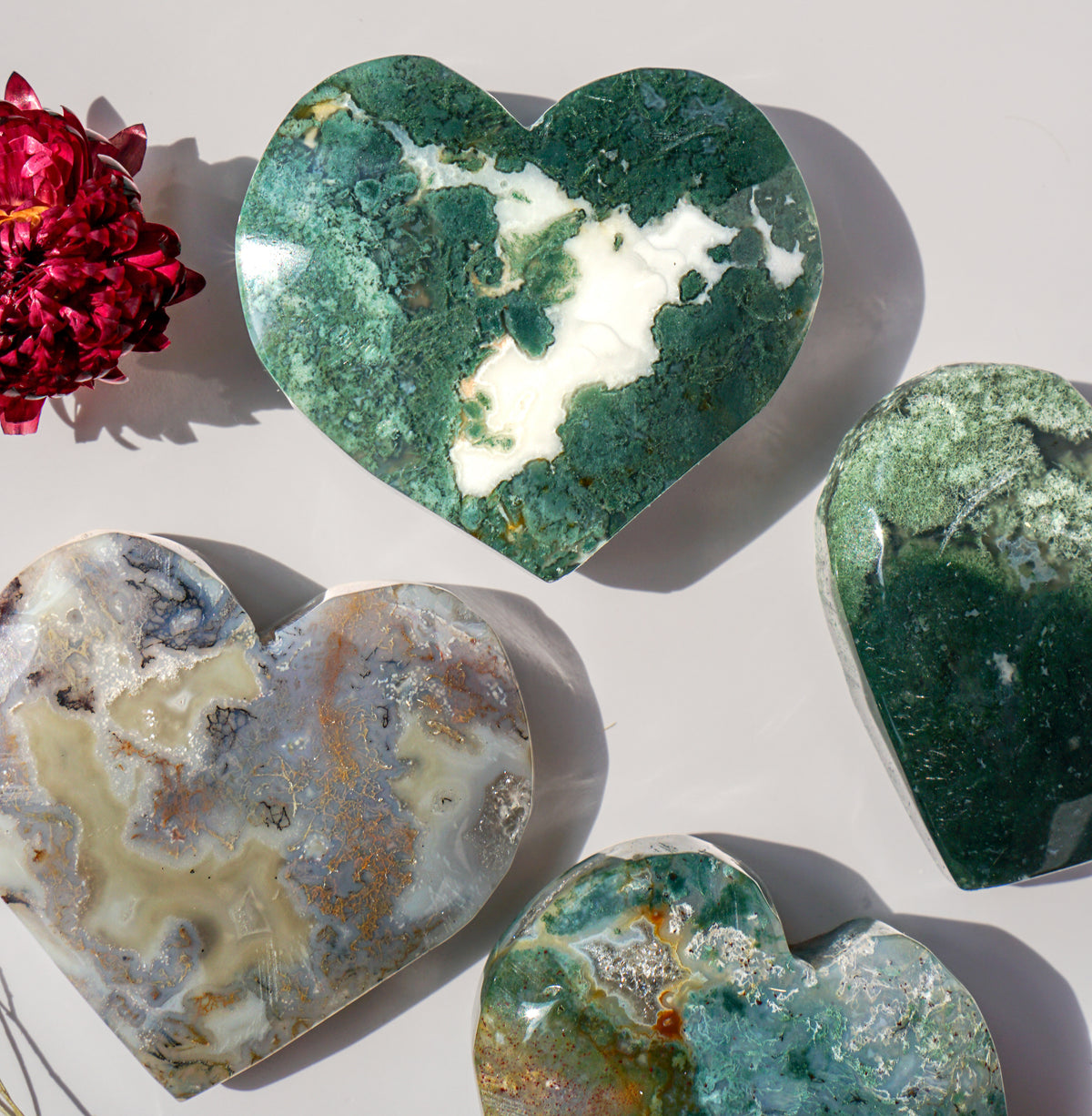 White plume moss agate heart carving grouped with grey and teal moss agate hearts