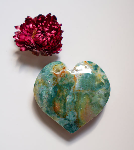 Close-up of a teal and rust-toned moss agate heart, alternate angle