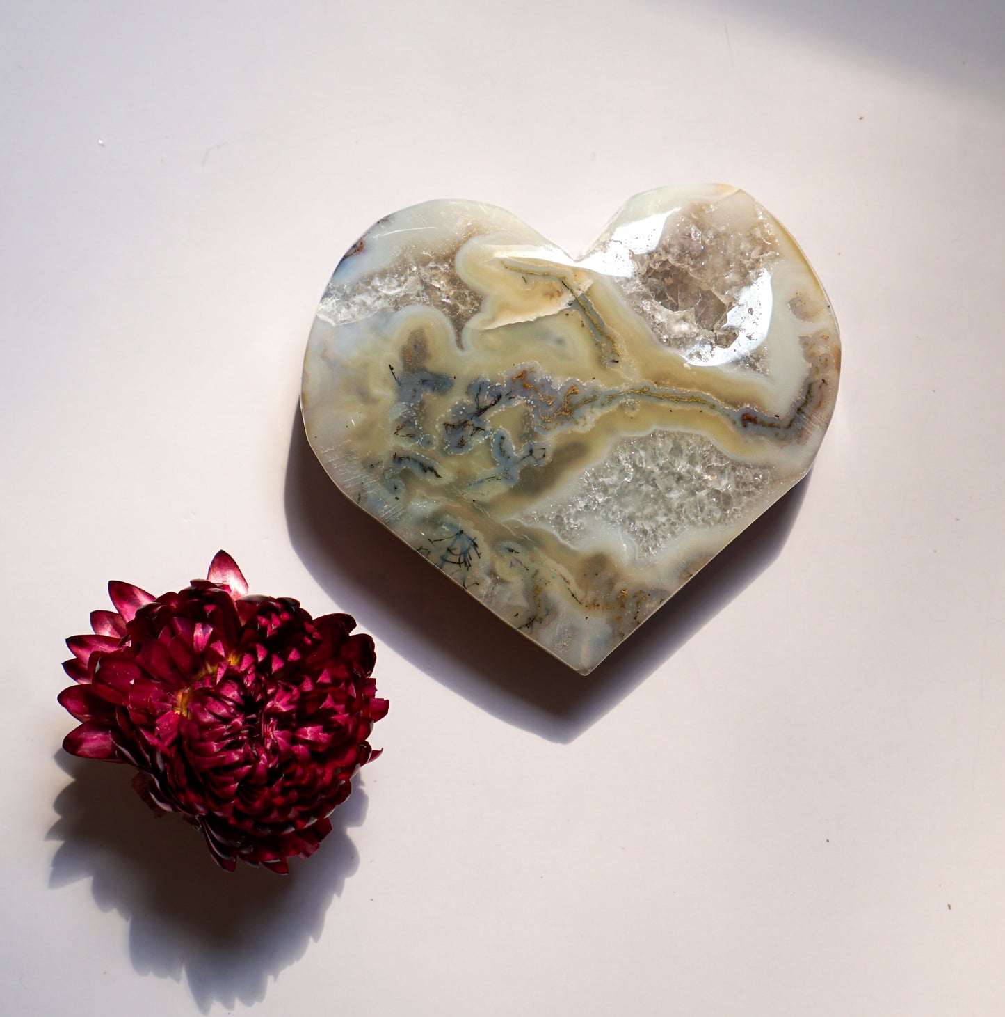 Close-up of a grey moss agate heart with warm amber veining, alternate angle