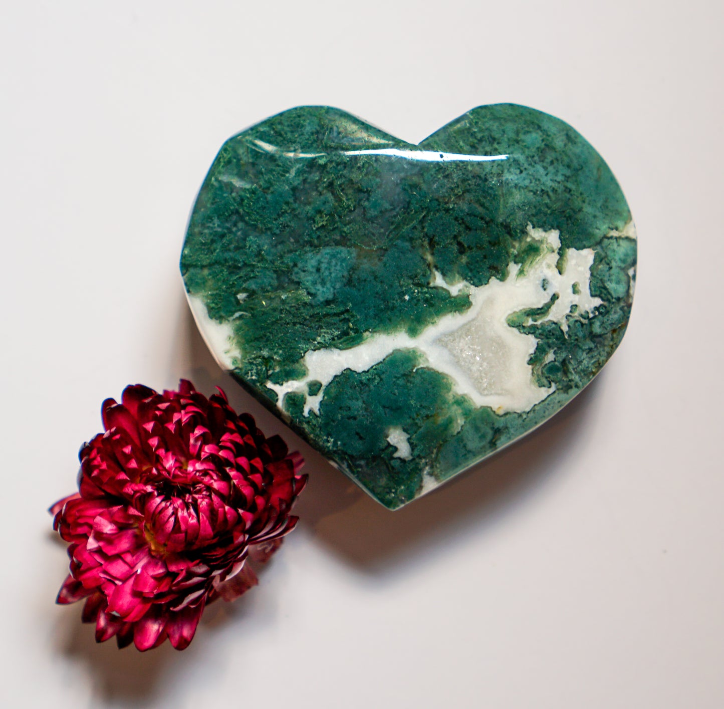 White plume moss agate heart carving with vivid green moss and a dried red flower