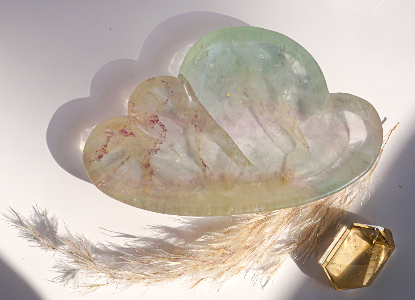 Close-up of rainbow fluorite cloud dish in ivory and pink banding with a citrine crystal point