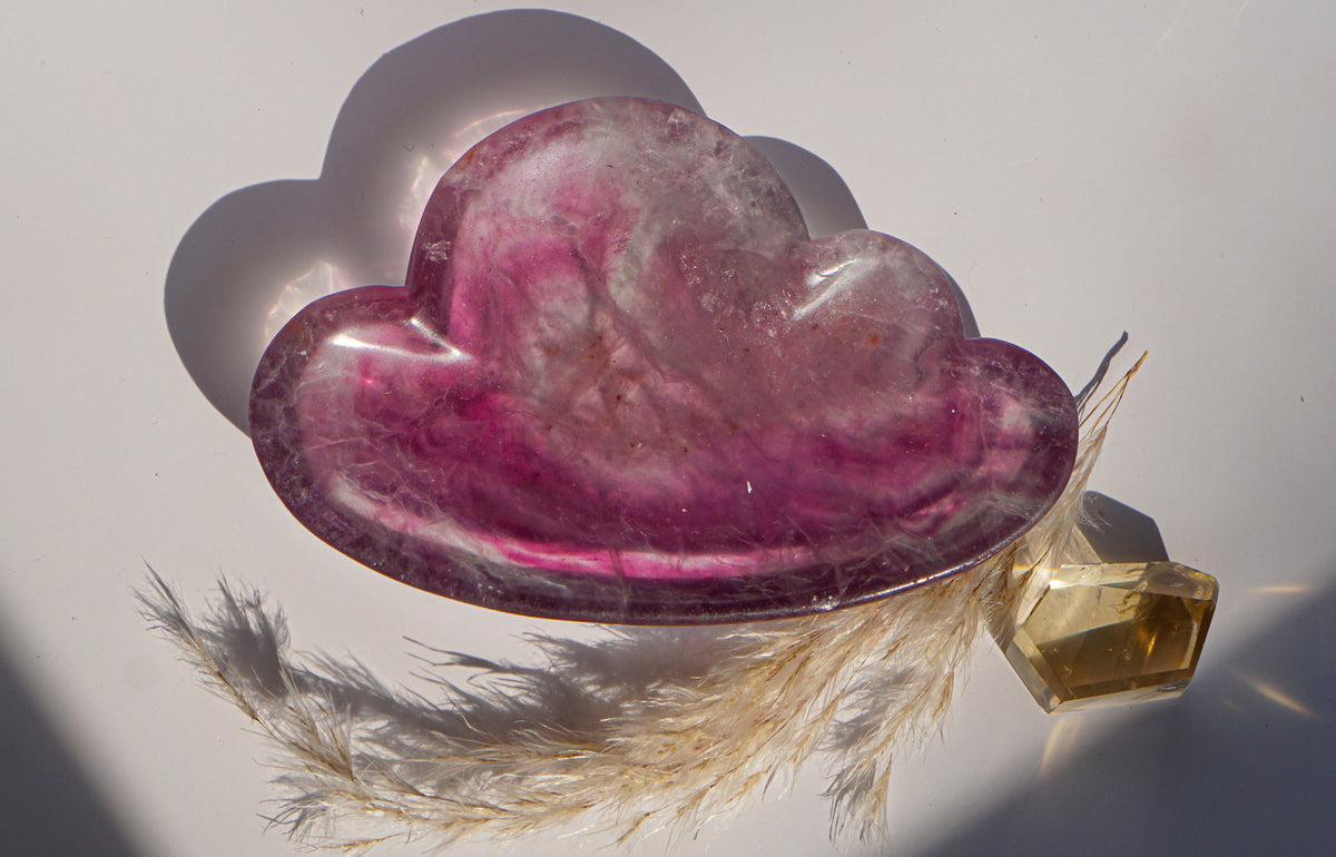 Close-up of rainbow fluorite cloud dish in rose and magenta banding with a citrine crystal point