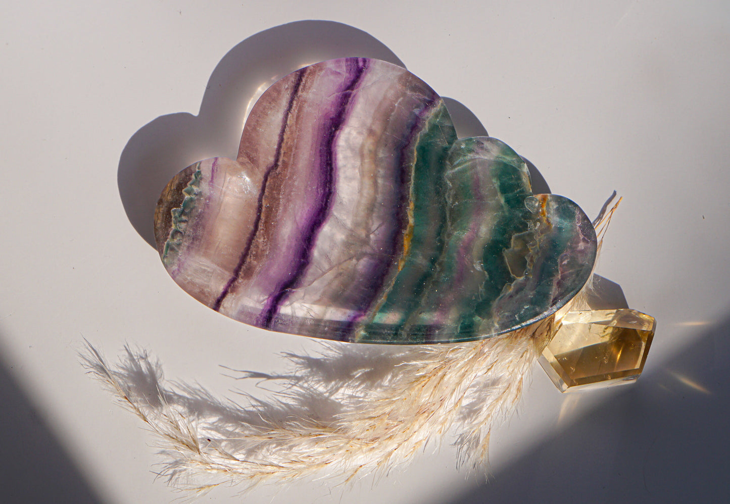 Rainbow fluorite cloud dish in purple and teal rainbow banding with a citrine crystal point and dried pampas grass