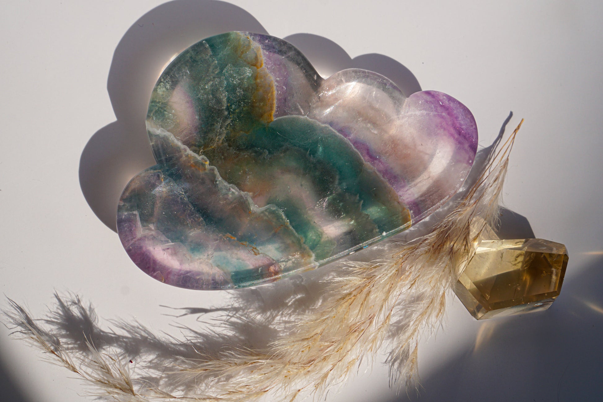 Rainbow fluorite cloud dish in teal and plum banding with a citrine crystal point and dried pampas grass