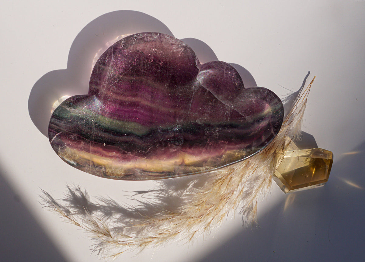 Close-up of rainbow fluorite cloud dish in purple and olive banding with a citrine crystal point