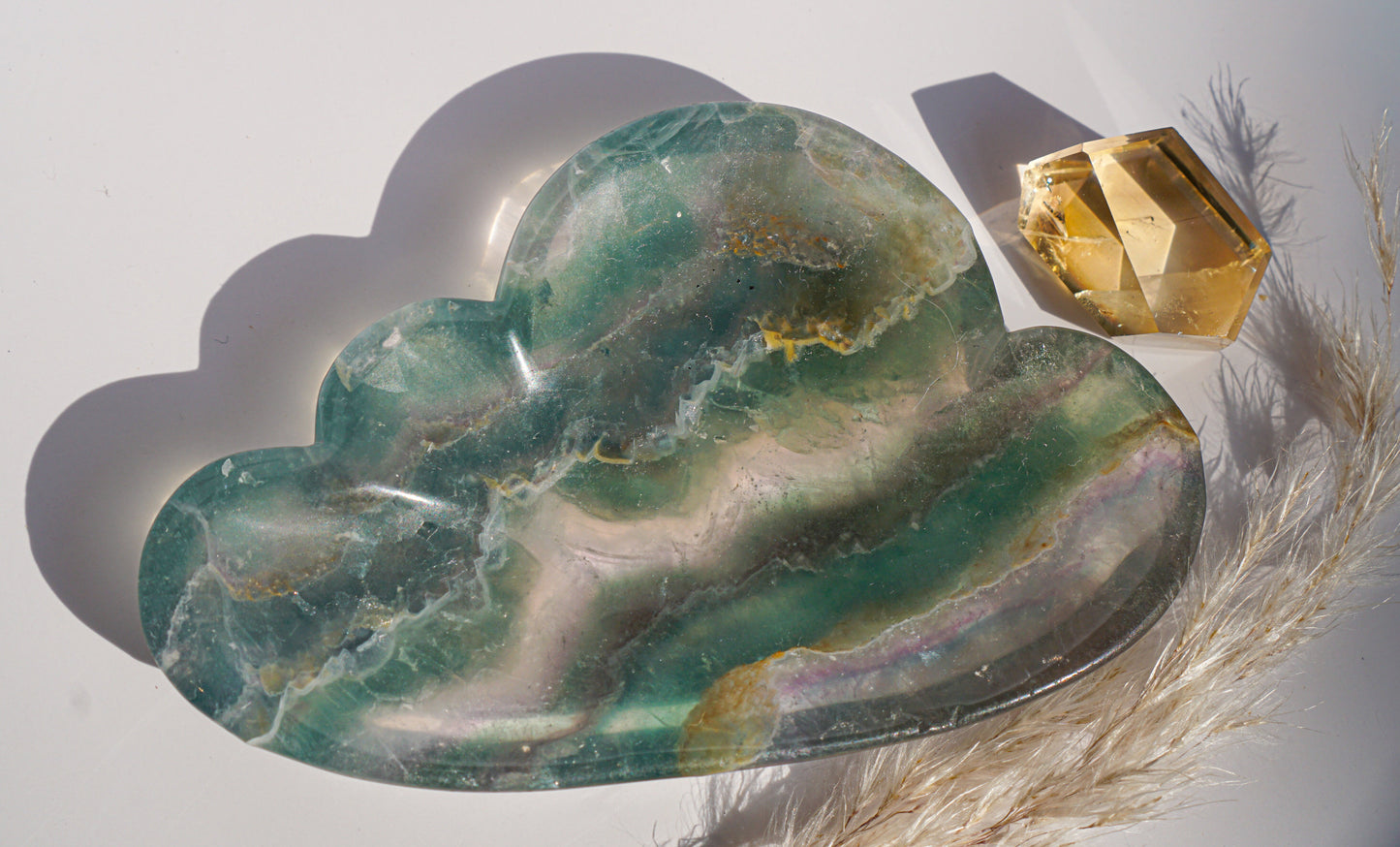 Rainbow fluorite cloud dish in purple and moss green banding with a citrine crystal point and dried pampas grass