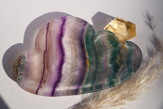 Rainbow fluorite cloud dish in purple and teal banding with a citrine crystal point