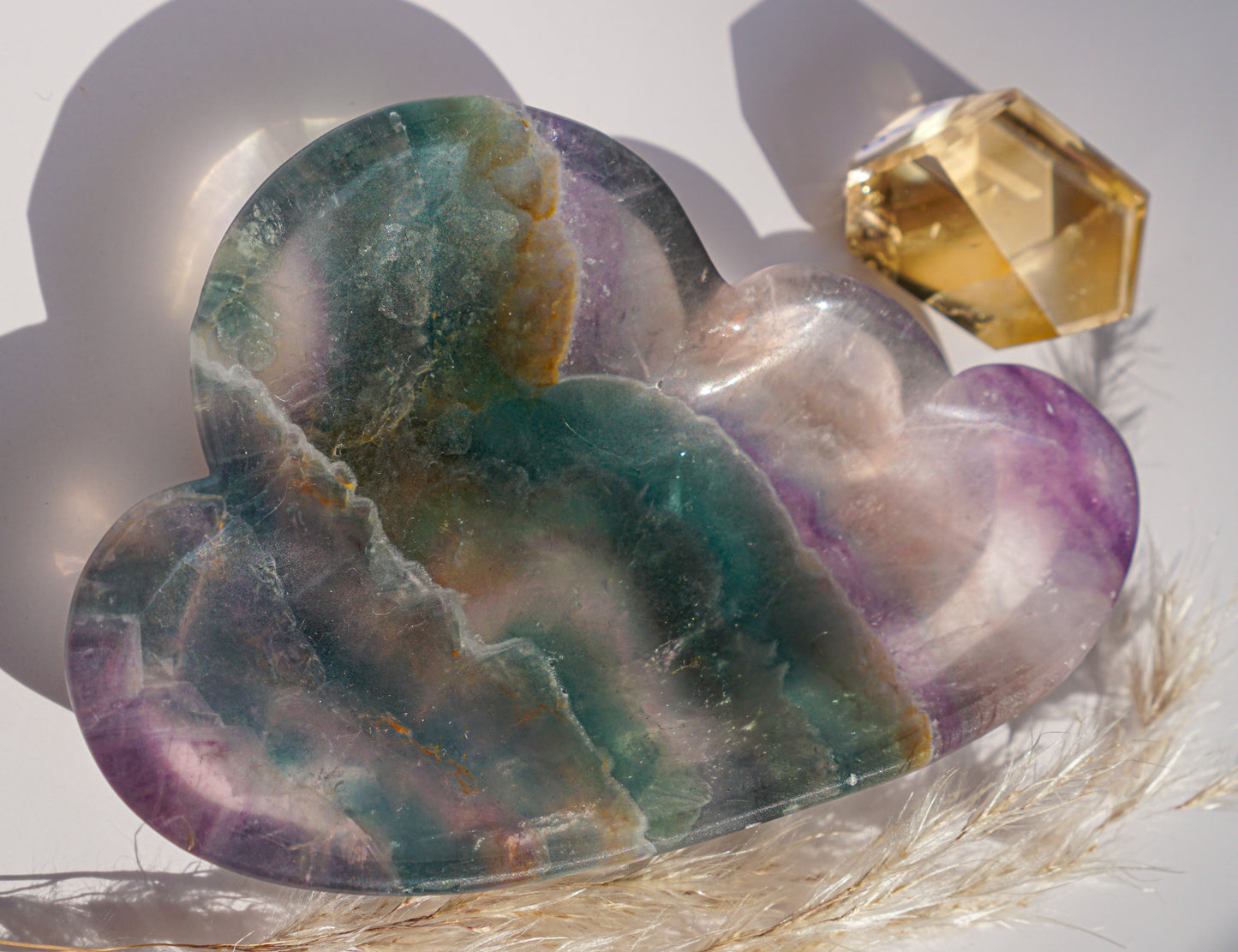 Close-up of rainbow fluorite cloud dish in teal and plum banding with a citrine crystal point