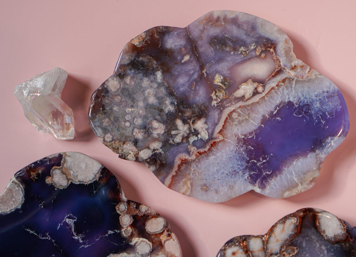 Blue Flower Agate dish with quartz crystal beside it on pink background