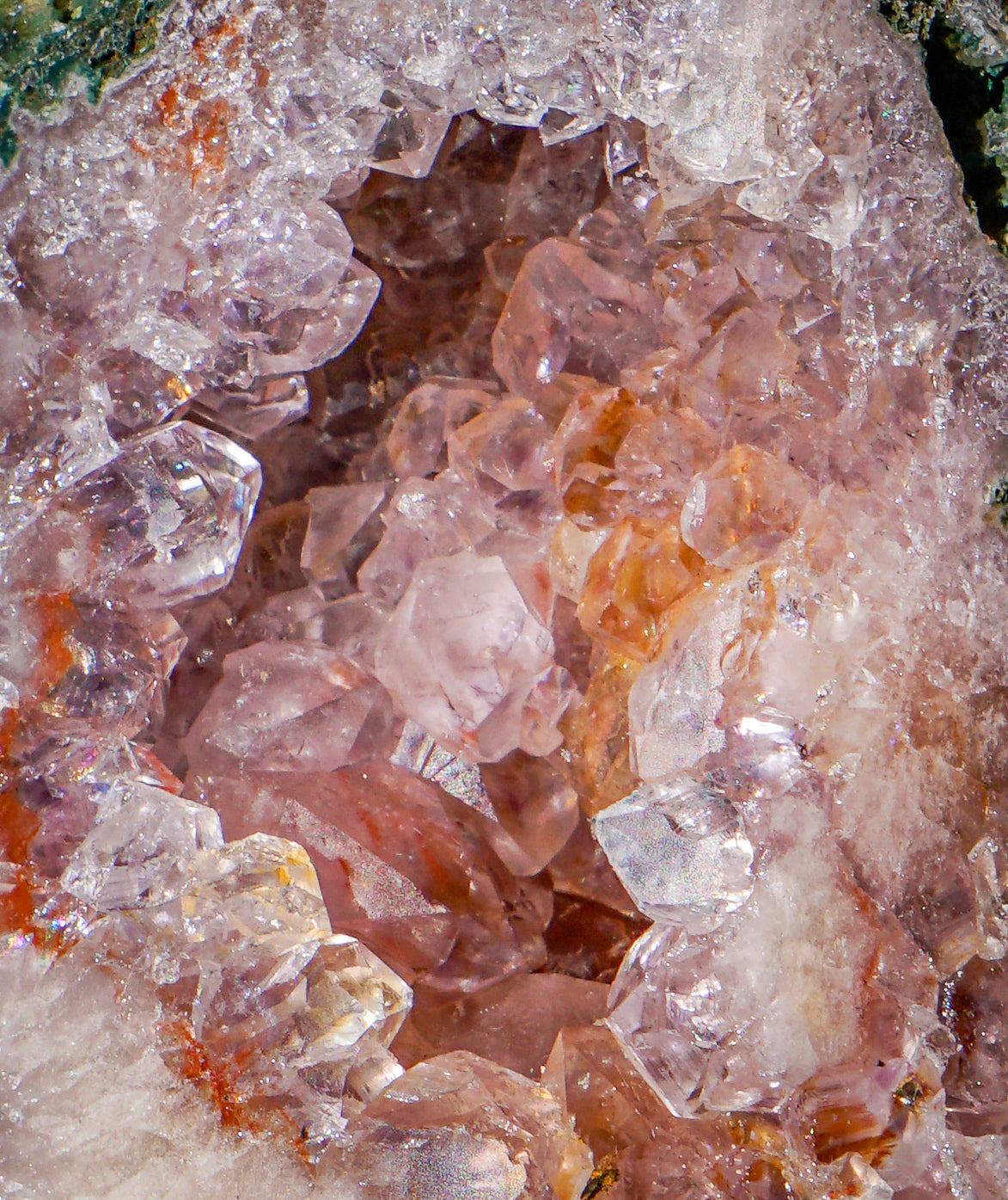 Close-up of a crystal pink amethyst and jasper crystal tower geode or mineral specimen with pale pink and clear quartz-like crystals forming a hollow interior, surrounded by white and orange mineral matrix.